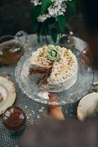 Ein dekorierter Kuchen wird auf einem kleinen Tisch im Garten serviert, Foto Kochbuch, TABLEDANCE, Food Fotografie, WINGMEN Media