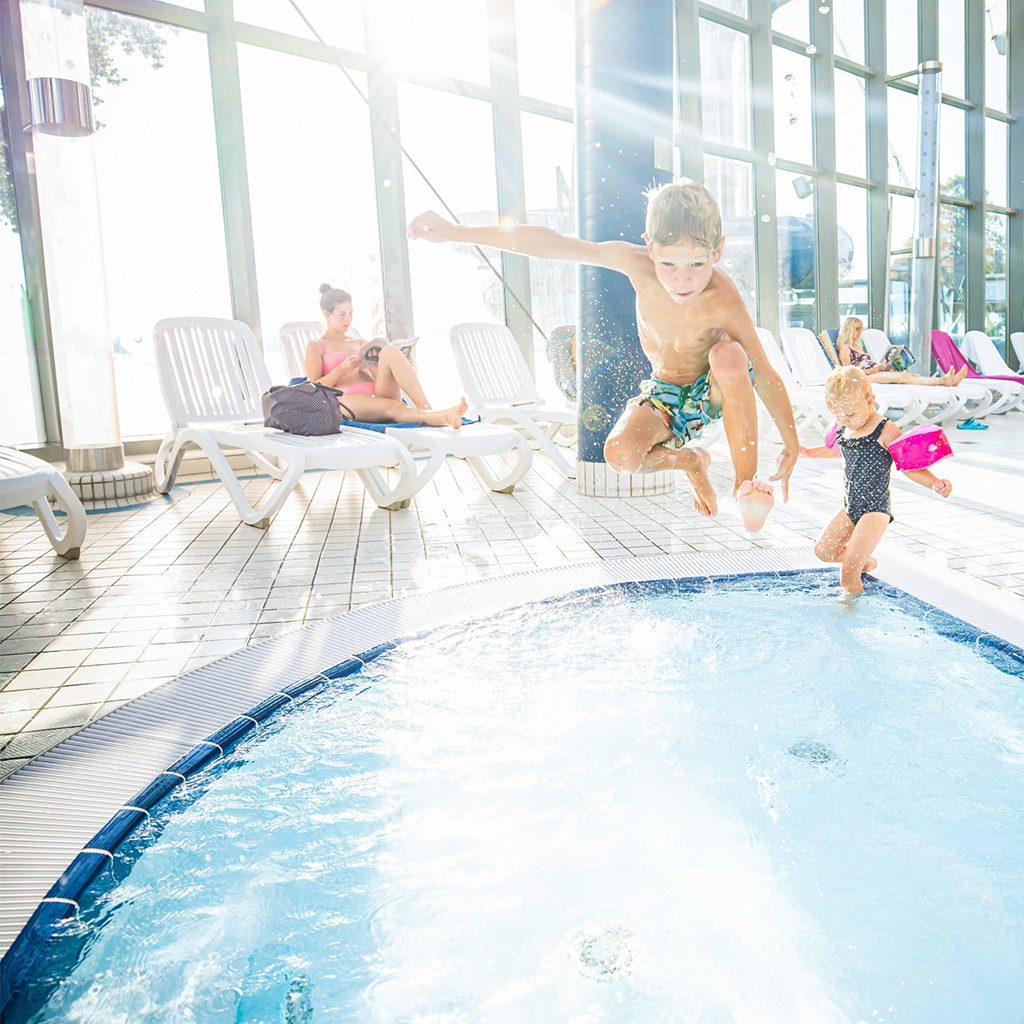 TOURISMUSFILM 48 Ein Junge springt in das Kinderbecken eines Schwimmbads, High-key, Prienavera Erlebnisbad & Strandbad, Lifestylefotografie, WINGMEN Media