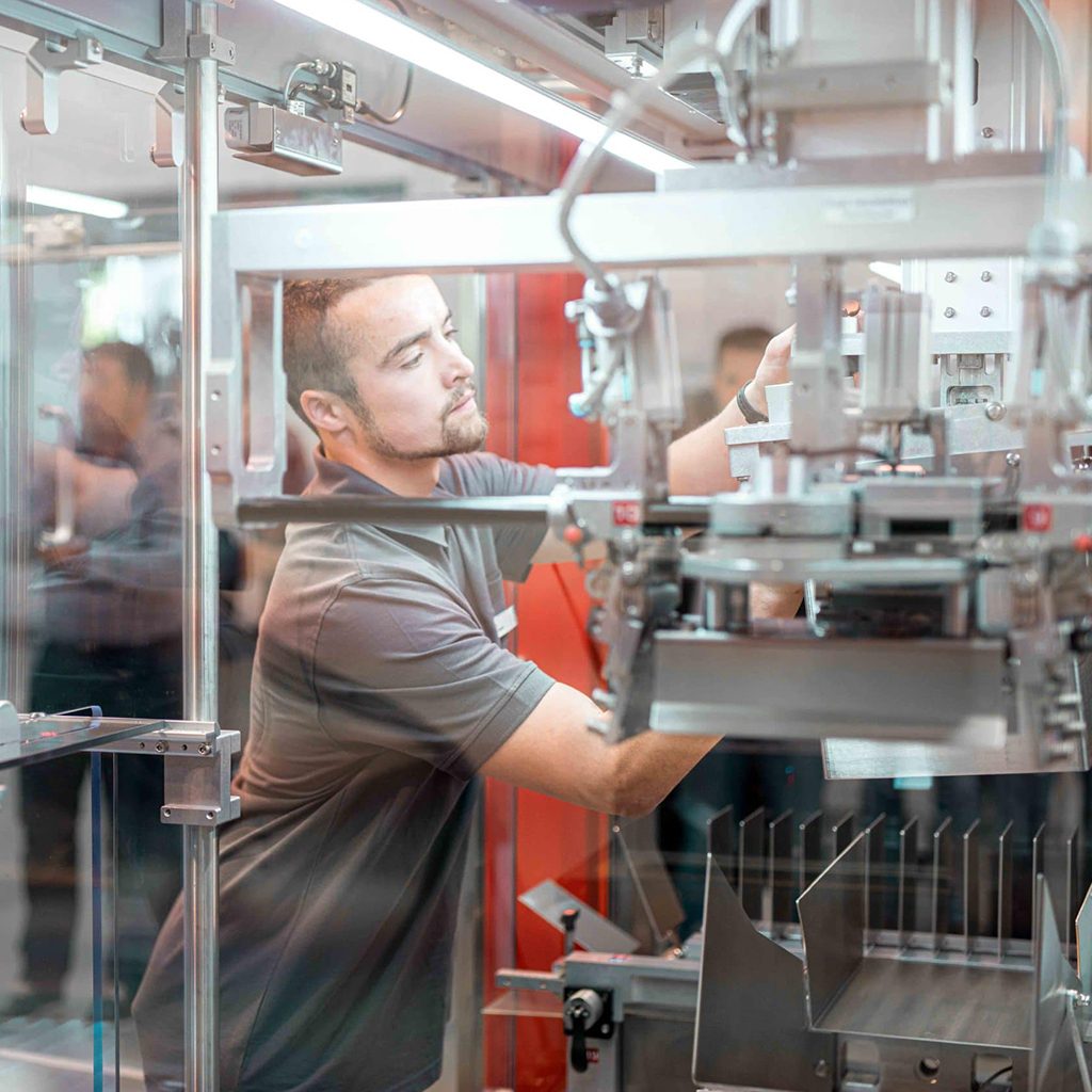 Mitarbeiterfotografie eines jungen Mannes bei Arbeit an Verpackungsmaschine, Somic GmbH, Unternehmensfotografie, WINGMEN Media