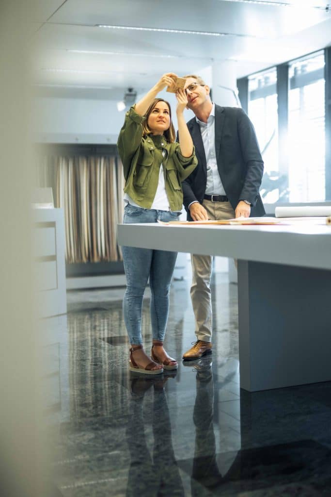zwei Personen bei Dekor Musterbetrachtung im Büro, Holzdekor Verkaufsgespräch, Schattdecor, Unternehmensfotografie, Behind The Scenes Fotografie, High-key, WINGMEN Media